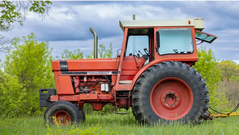 Vintage red International tractor parked in a green pasture