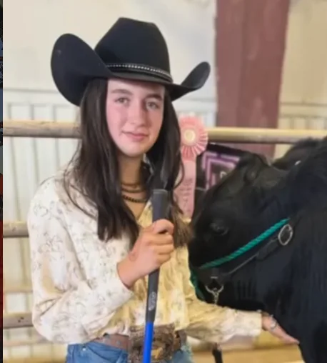 Portrait of Maddie in a cowboy hat with her show steer and ribbon